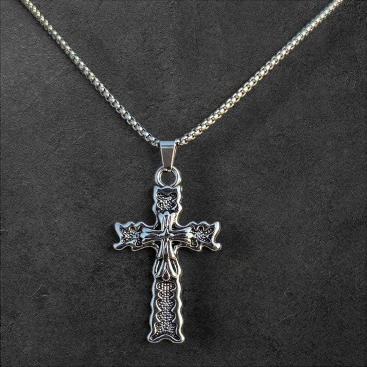 Silver-toned ornate filigree cross pendant necklace with textured vintage-inspired detailing on a sturdy chain.
